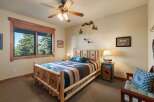 Experience rustic charm in this cozy bedroom, featuring a log-style bed adorned with a vibrant geometric blanket and a plush accent pillow.
