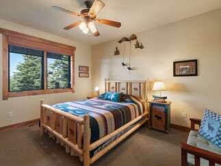 Experience rustic charm in this cozy bedroom, featuring a log-style bed adorned with a vibrant geometric blanket and a plush accent pillow.