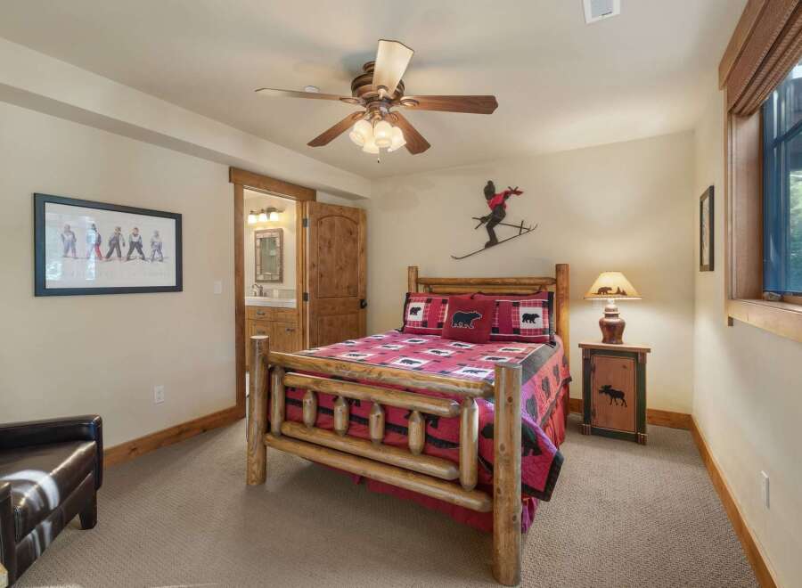 Experience rustic charm in this cozy bedroom featuring a log-style bed adorned with bear-themed linens.