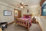 Experience rustic charm in this cozy bedroom featuring a log-style bed adorned with bear-themed linens.