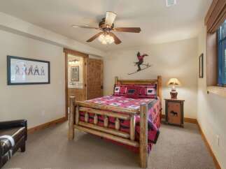 Experience rustic charm in this cozy bedroom featuring a log-style bed adorned with bear-themed linens.