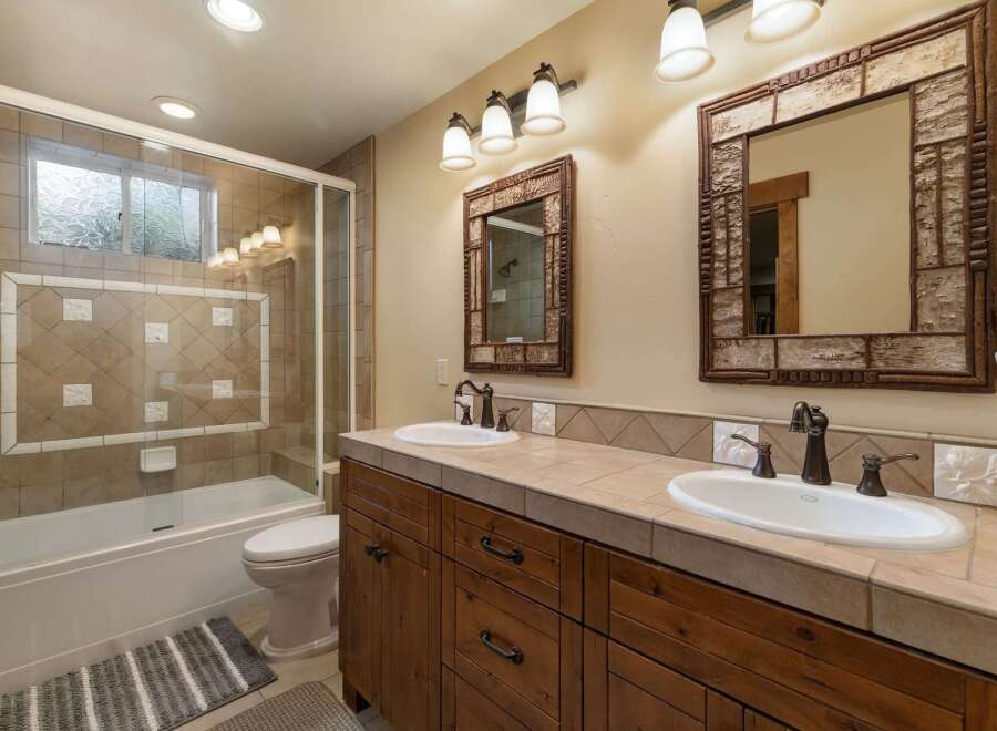 This charming bathroom features a spacious bathtub with a glass enclosure and decorative tile accents.