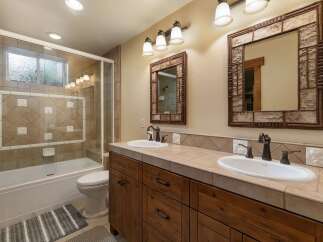 This charming bathroom features a spacious bathtub with a glass enclosure and decorative tile accents.