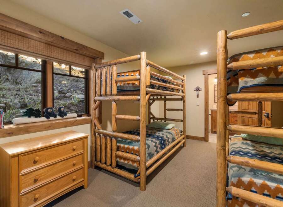 Experience rustic charm in this bedroom featuring a triple bunk bed crafted from natural logs, perfect for accommodating guests or family.