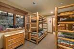 Experience rustic charm in this bedroom featuring a triple bunk bed crafted from natural logs, perfect for accommodating guests or family.