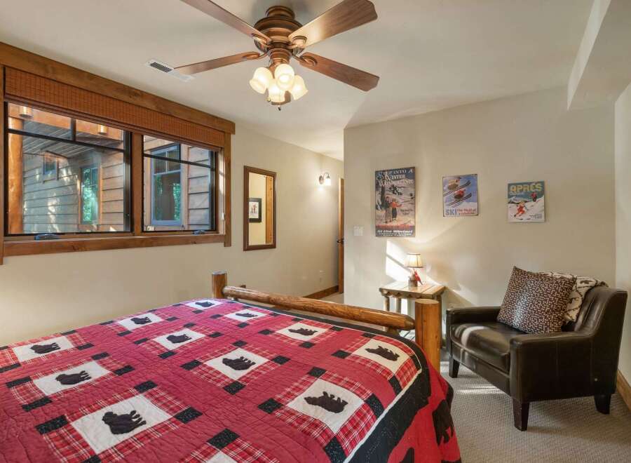 Experience rustic charm in this cozy bedroom, featuring a comfortable log bed adorned with a charming bear-themed quilt.