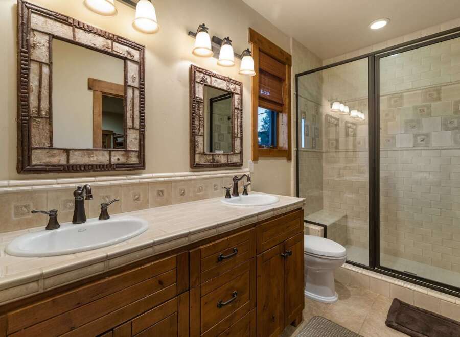 This rustic bathroom features a double vanity with unique twig-framed mirrors and oil-rubbed bronze fixtures.