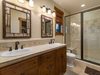 This rustic bathroom features a double vanity with unique twig-framed mirrors and oil-rubbed bronze fixtures.