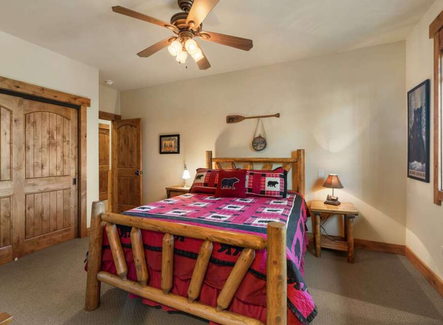 Experience rustic charm in this cozy bedroom, featuring a beautiful log bed adorned with bear-themed linens and pillows.
