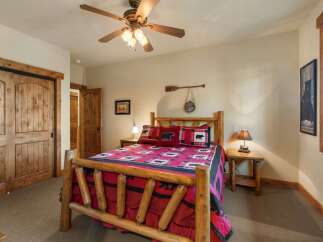 Experience rustic charm in this cozy bedroom, featuring a beautiful log bed adorned with bear-themed linens and pillows.