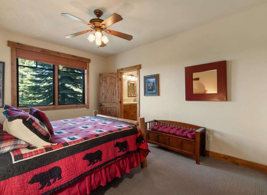 Experience rustic charm in this cozy bedroom featuring a comfortable bed with a bear-themed quilt and plush pillows.
