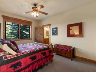 Experience rustic charm in this cozy bedroom featuring a comfortable bed with a bear-themed quilt and plush pillows.