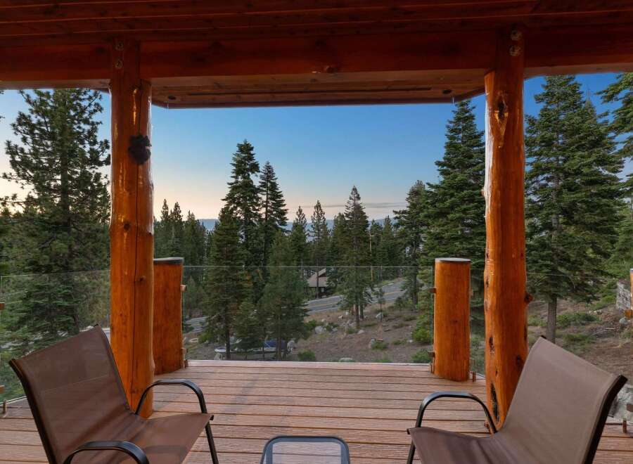 Enjoy breathtaking mountain views from this stunning log cabin deck, complete with comfortable seating and a glass railing for unobstructed scenery.