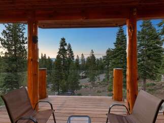 Enjoy breathtaking mountain views from this stunning log cabin deck, complete with comfortable seating and a glass railing for unobstructed scenery.