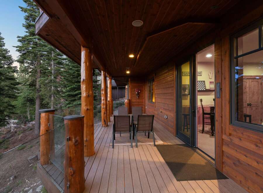 Experience the perfect blend of rustic charm and modern comfort on this expansive wooden deck, nestled amongst towering pine trees.