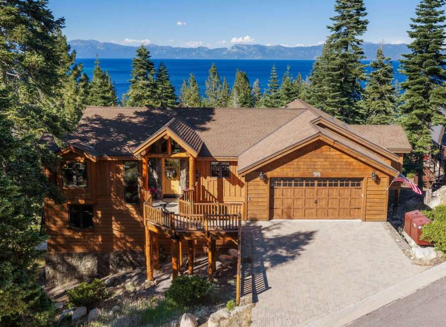 Experience breathtaking lake and mountain views from this stunning wooden home, nestled amidst tall pine trees.