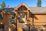 Experience rustic charm in this mountain retreat featuring a beautiful log-accented entrance with a stone facade and a welcoming wooden door adorned with a wreath.