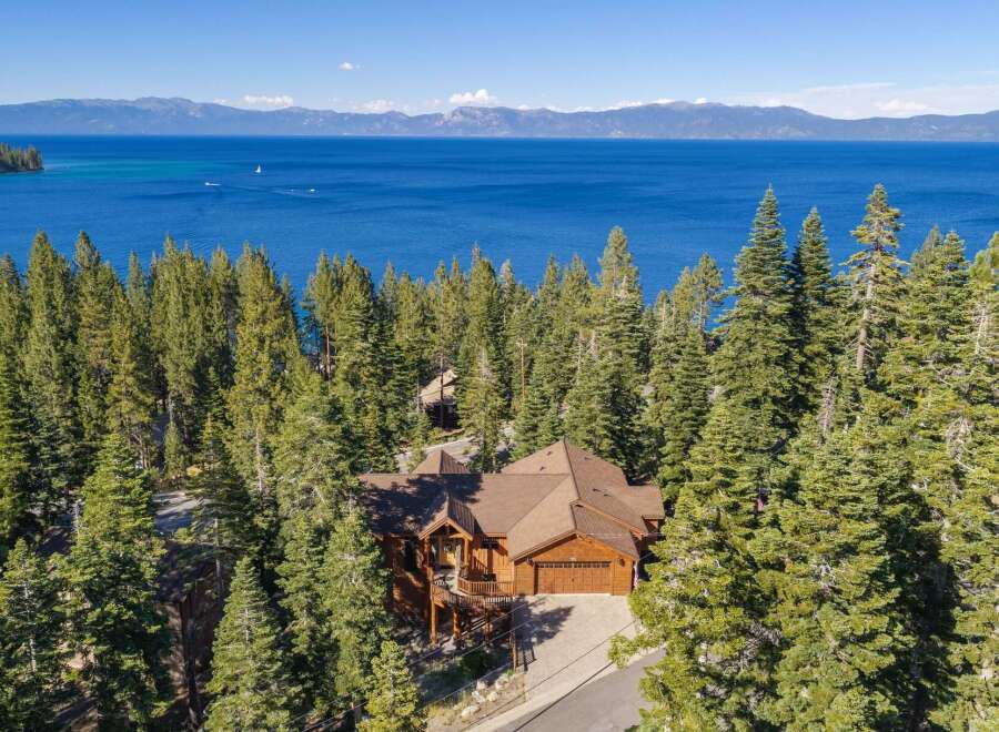 Experience luxury living in this stunning lakefront property, nestled amidst towering pine trees with breathtaking views of the azure water and distant mountains.
