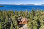 Experience luxury living in this stunning lakefront property, nestled amidst towering pine trees with breathtaking views of the azure water and distant mountains.