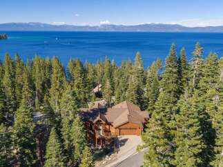 Experience luxury living in this stunning lakefront property, nestled amidst towering pine trees with breathtaking views of the azure water and distant mountains.