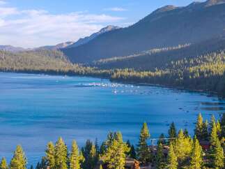 Experience the ultimate lakeside living with this stunning property offering breathtaking views of a serene blue lake and majestic mountains.
