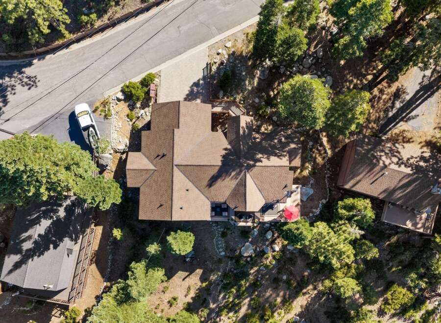 Discover this stunning aerial view of a multi-level home nestled amidst lush trees and natural rock formations.