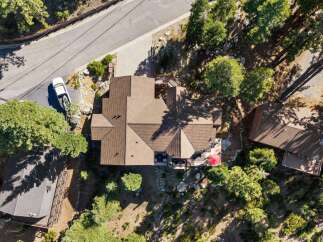 Discover this stunning aerial view of a multi-level home nestled amidst lush trees and natural rock formations.