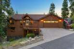 Experience rustic charm in this stunning wood-sided home, featuring a welcoming covered porch with a wooden deck and stone accents.