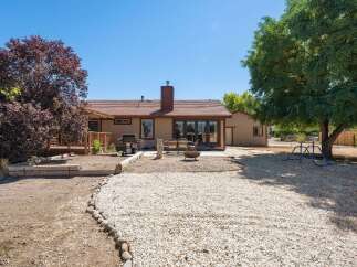 Enjoy outdoor living with this spacious backyard featuring a large deck, a patio area with seating, and a fire pit perfect for gatherings.