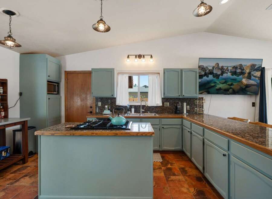 This spacious kitchen boasts light blue cabinetry and granite countertops, offering a modern and inviting atmosphere.