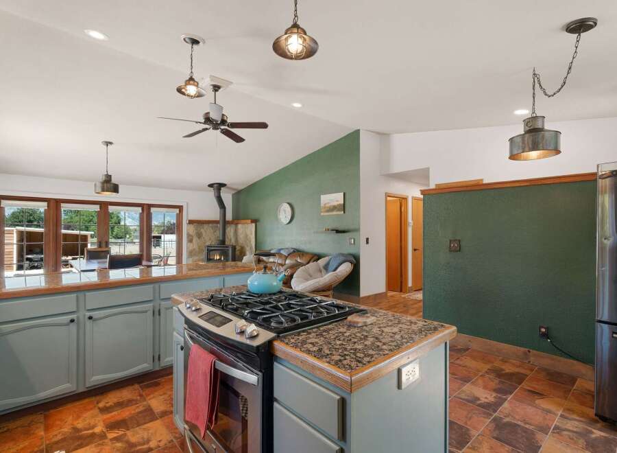 This spacious kitchen boasts a charming rustic aesthetic with a central island featuring a gas range and granite countertops.