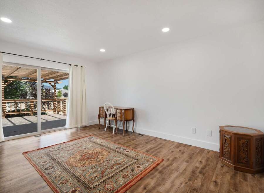 Step into this inviting living space featuring a large sliding glass door that opens to a spacious deck and pergola, perfect for outdoor entertaining.