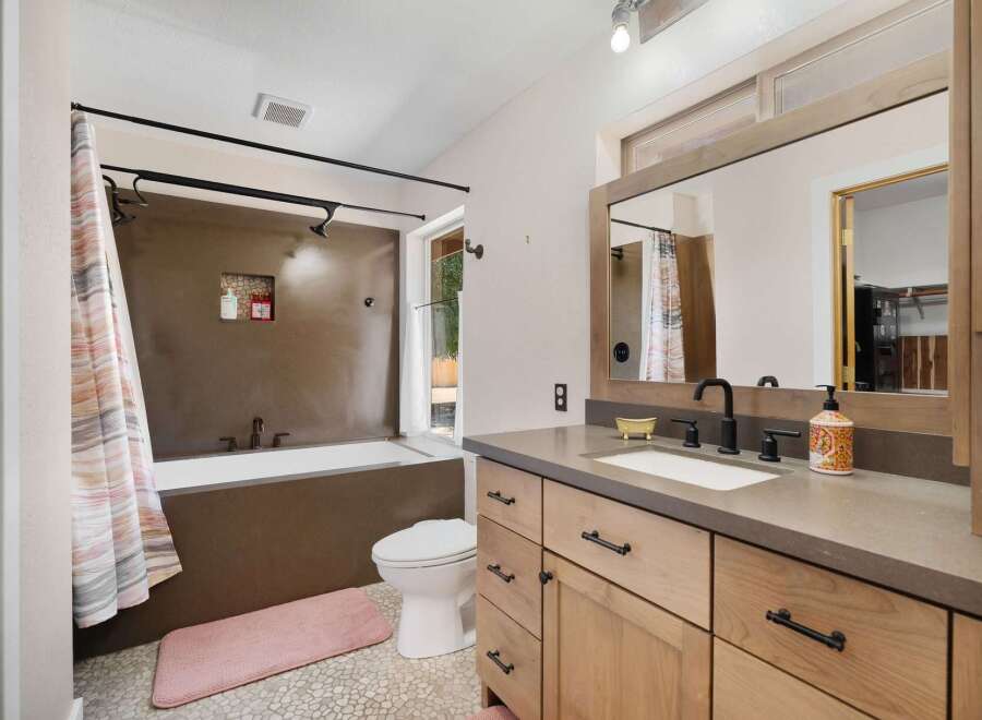 This modern bathroom features a sleek design with a deep soaking tub and a separate toilet area.