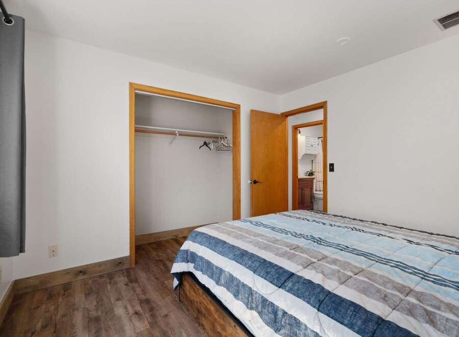 Discover comfort and convenience in this inviting bedroom, featuring a spacious closet and a charming ensuite bathroom visible through the open doorway.