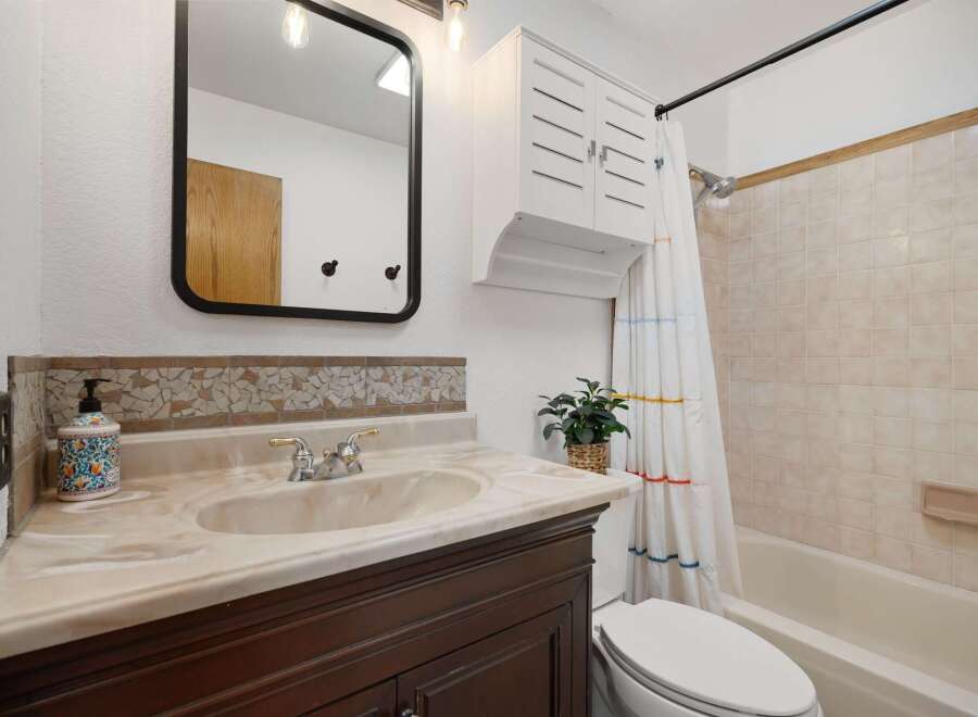 This charming bathroom features a stylish vanity with a marble countertop and a decorative mosaic backsplash.