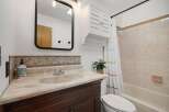 This charming bathroom features a stylish vanity with a marble countertop and a decorative mosaic backsplash.