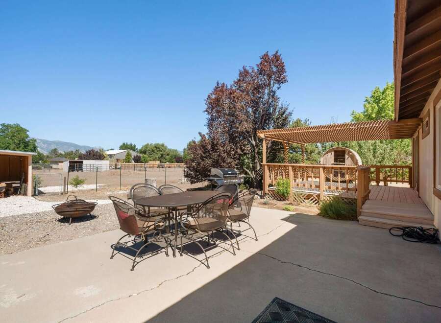 Enjoy outdoor living with this spacious backyard featuring a concrete patio, a fire pit, and a gas grill perfect for entertaining.