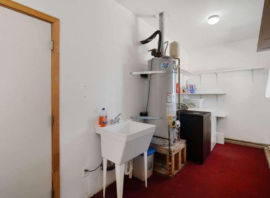 This laundry room features a large utility sink and a tall water heater, perfect for handling household chores.