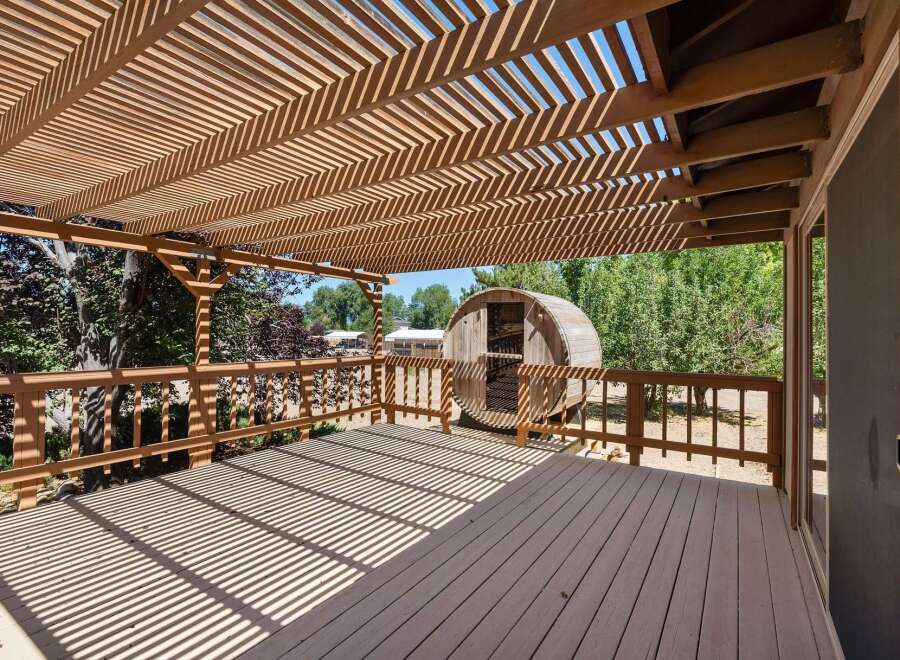 Enjoy outdoor living on this spacious wooden deck, complete with a charming wooden barrel structure perfect for relaxation or entertaining.