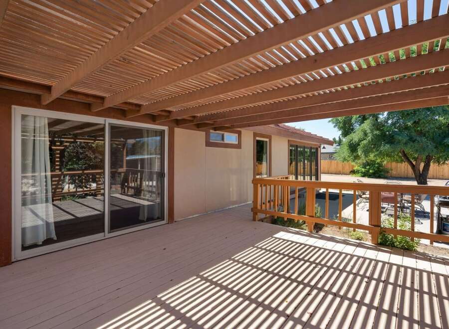Enjoy outdoor living under this expansive wooden pergola, offering dappled shade over a spacious deck.