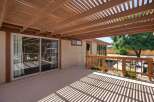 Enjoy outdoor living under this expansive wooden pergola, offering dappled shade over a spacious deck.