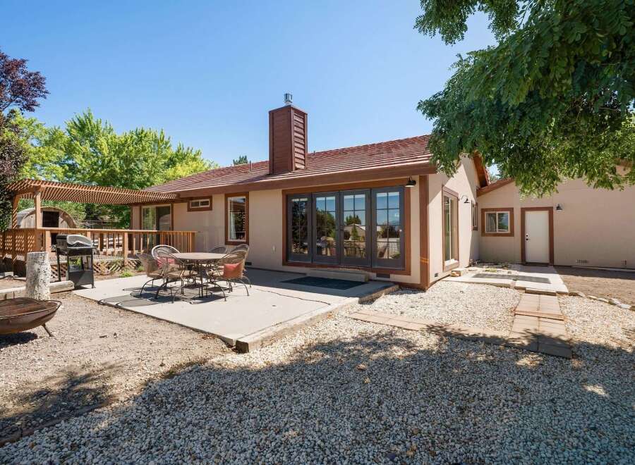 Enjoy outdoor living with this charming backyard featuring a spacious deck, a covered pergola, and a concrete patio perfect for entertaining.