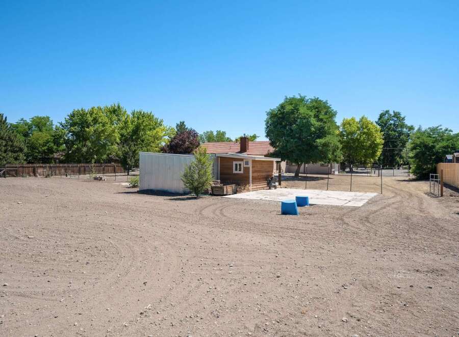 Discover potential on this expansive lot, featuring a charming wooden structure and a large metal shed, perfect for storage or a workshop.
