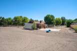 Discover potential on this expansive lot, featuring a charming wooden structure and a large metal shed, perfect for storage or a workshop.