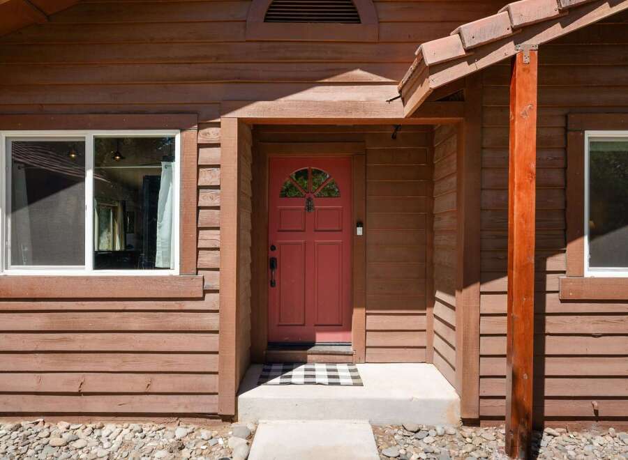 Step into this charming home featuring a welcoming red front door with a decorative arched window, perfect for greeting guests.
