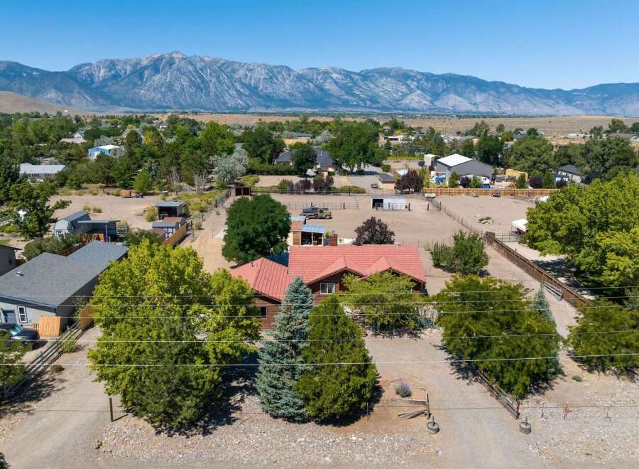 Discover this expansive property featuring a charming home with a red tile roof, nestled amidst mature trees and offering stunning mountain views.
