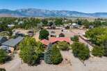Discover this expansive property featuring a charming home with a red tile roof, nestled amidst mature trees and offering stunning mountain views.