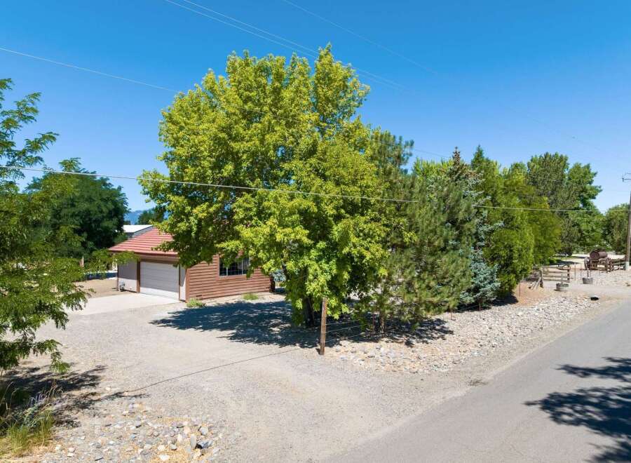 Discover this charming property featuring a spacious garage with a warm, wood-sided exterior and a classic red tile roof.