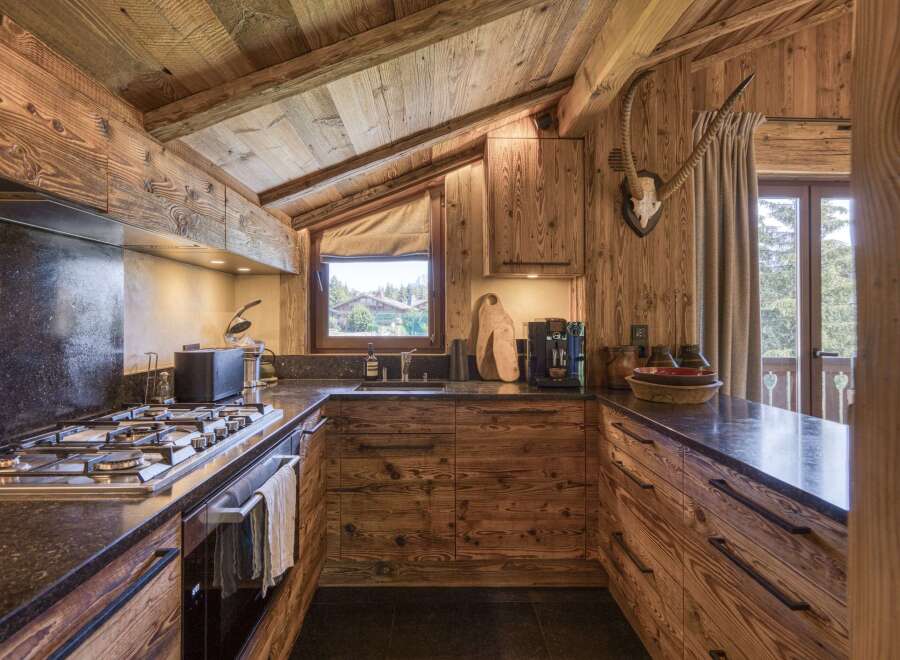 Experience rustic charm in this mountain kitchen, featuring warm wooden cabinetry and exposed beams that create a cozy, inviting atmosphere.