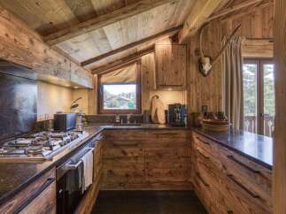 Experience rustic charm in this mountain kitchen, featuring warm wooden cabinetry and exposed beams that create a cozy, inviting atmosphere.